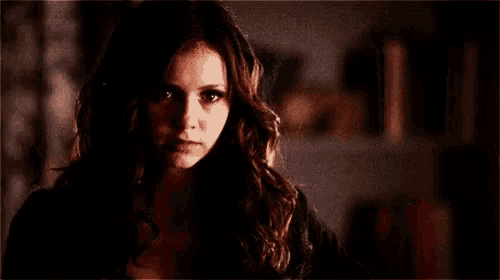 a close up of a woman 's face in a dark room with a serious look on her face .