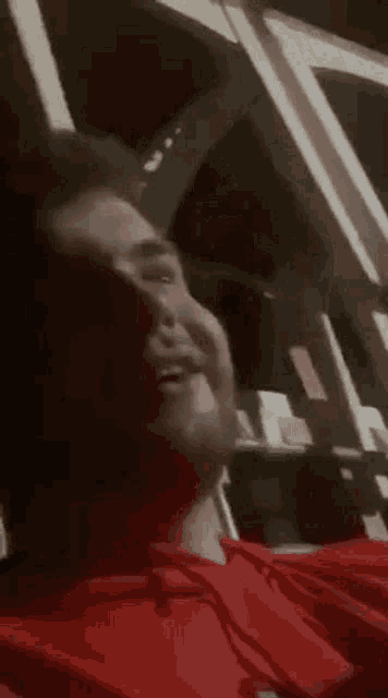 a man in a red shirt is sitting in a car looking out a window .