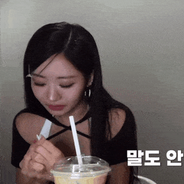 a woman with long black hair is drinking from a plastic cup