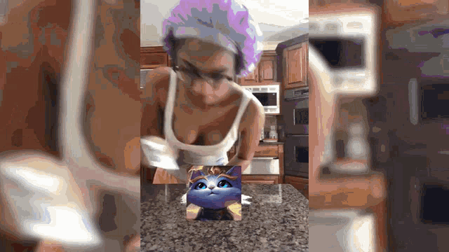 a woman with purple hair is holding a picture of a cat on a table