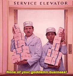 two men are holding boxes in front of a service elevator