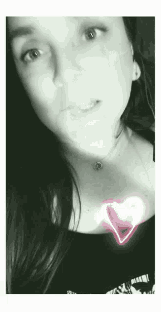 a black and white photo of a woman with a heart shaped necklace
