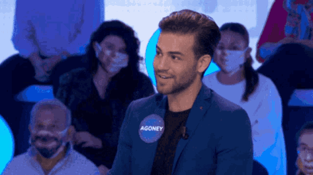 a man in a blue suit has a name tag with agoney on it