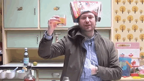 a man with a bag on his head is holding a glass of liquid