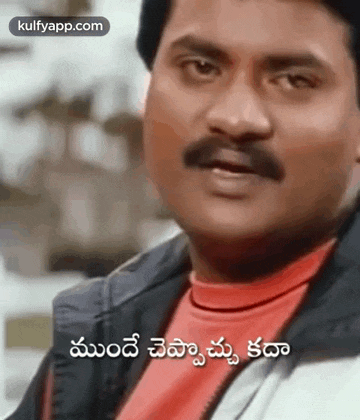 a man with a mustache is wearing a red shirt and a black jacket and is talking in a foreign language .