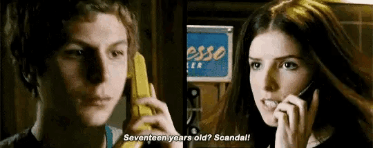a man and a woman are talking on a yellow phone and the woman is asking the man if he is seventeen years old .