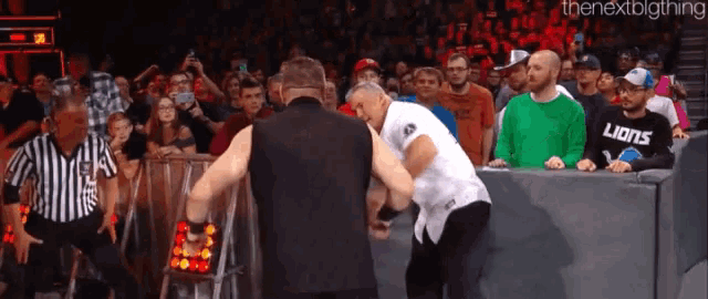 two men are wrestling in front of a crowd and one of them is wearing a lions shirt