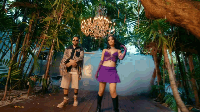 a man and a woman are standing in front of a chandelier in a jungle