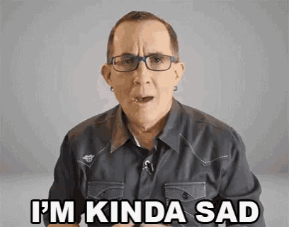 a man wearing glasses and a black shirt is making a sad face .