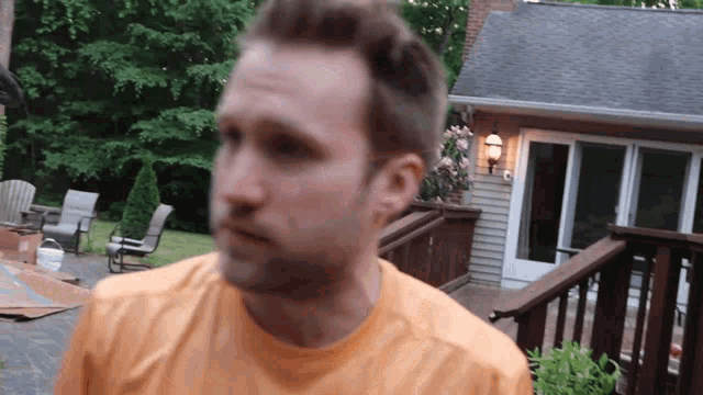 a man in an orange shirt is standing on a deck