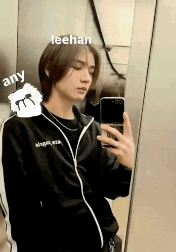 a young man is taking a selfie in a mirror with his phone .