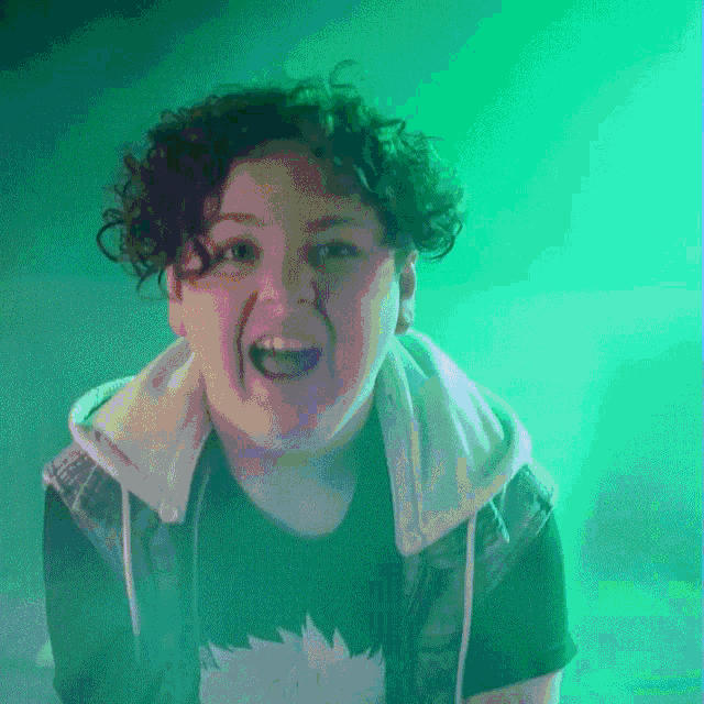 a woman with curly hair is wearing a hoodie and a black shirt