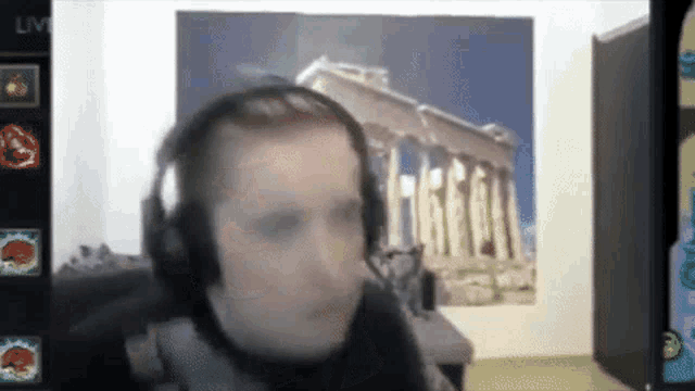 a man wearing headphones is sitting in front of a wall with a picture of a building behind him .