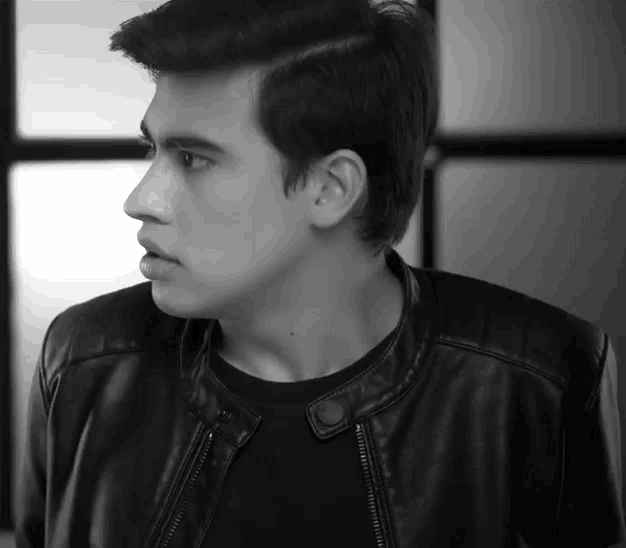 a young man wearing a black leather jacket and a black shirt