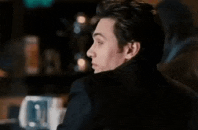 a man is sitting at a bar making a funny face and looking over his shoulder .