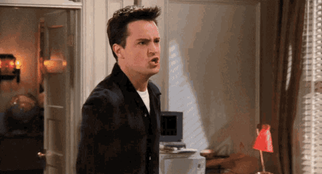 a man in a black jacket is making a funny face in a room