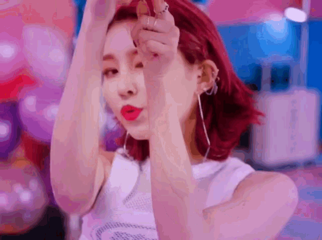 a woman with red hair is wearing earrings and a white tank top
