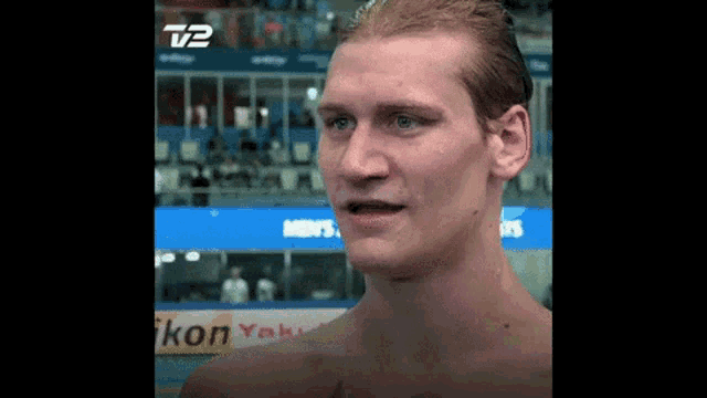 a shirtless man stands in front of a sign that says t2