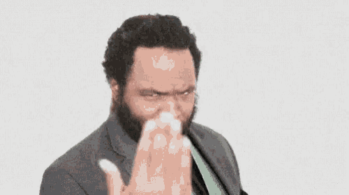 a man with a beard is wearing a suit and tie and making a face .