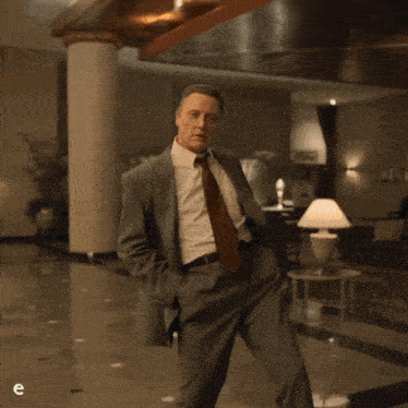 a man in a suit and tie walking in a hallway