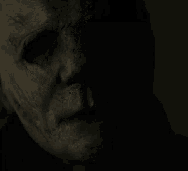 a close up of a person 's face in the dark with a scary mask on .
