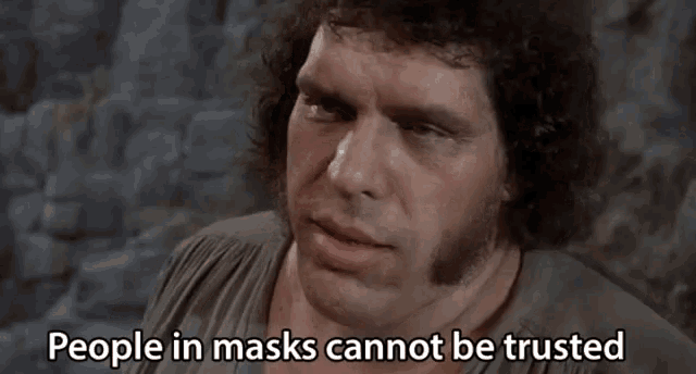 a man says people in masks cannot be trusted in front of a stone wall