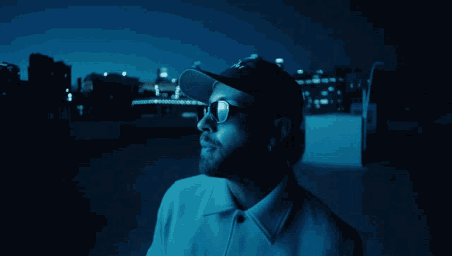 a man wearing a hat and glasses looks up at the sky