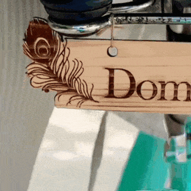 a wooden sign with the word dom and a peacock feather on it