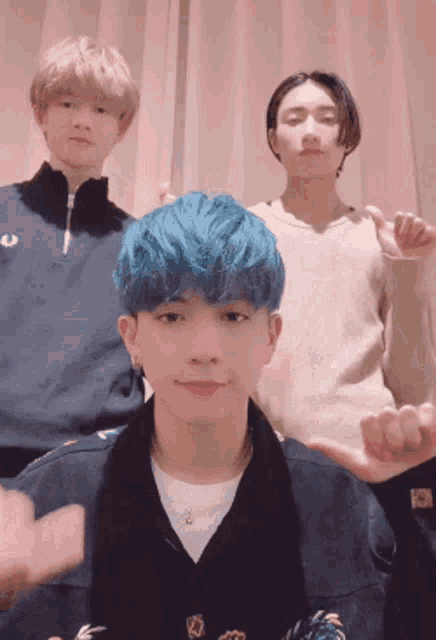 a man with blue hair is standing next to two other people