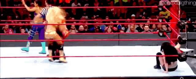 a woman is laying on the ground in a wrestling ring .