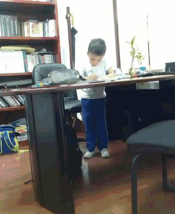 a little boy is standing at a desk with a pencil case that says ' pencil ' on it