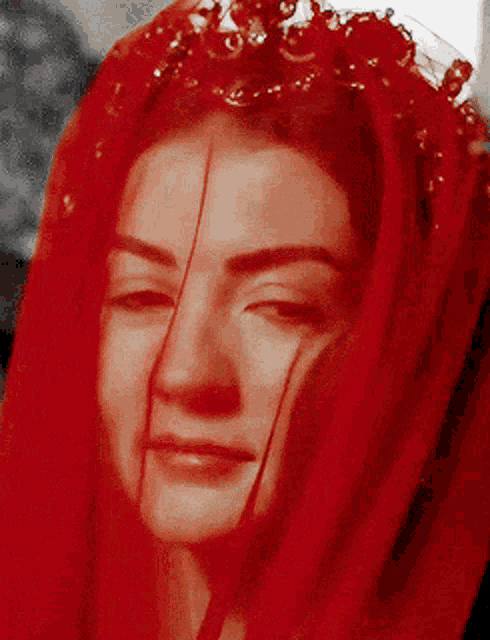 a woman wearing a red veil with a tiara on her head