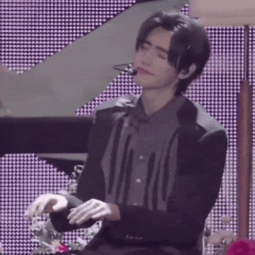 a man in a suit and tie is sitting in front of a piano and playing the piano .