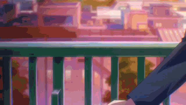 a person standing on a balcony overlooking a city with a green railing
