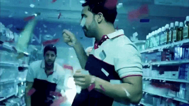 a man in a polo shirt is dancing in a store with confetti falling from the ceiling