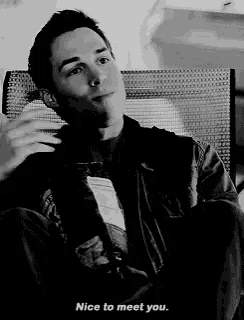 a black and white photo of a man sitting in a chair and saying nice to meet you