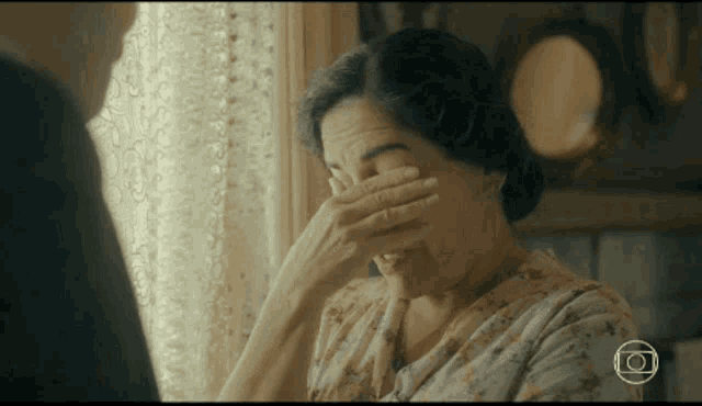 a woman is covering her face with her hand and smiling