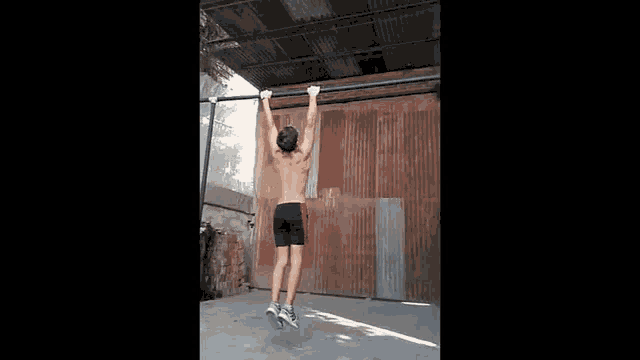 a man is doing a pull up on a bar in front of a rusty gate .