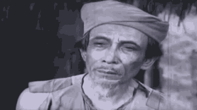 a black and white photo of an older man wearing a turban .