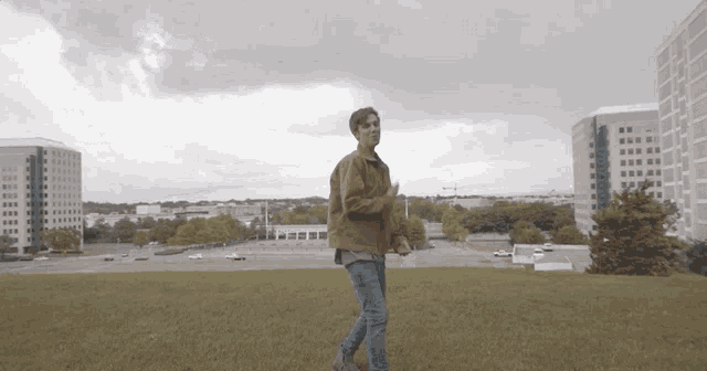 a man in a brown jacket walking on a grassy hill