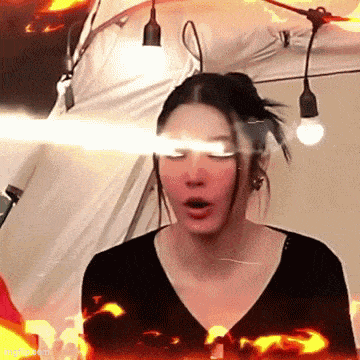 a woman wearing headphones is standing in front of a tent with a light shining on her face .