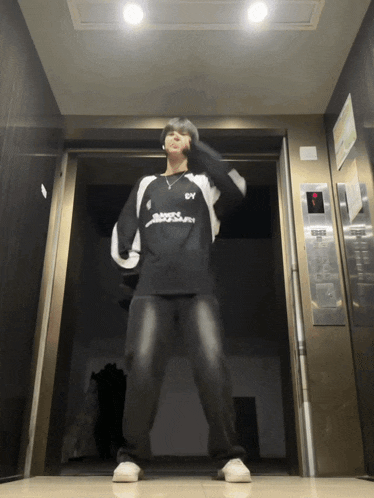 a man standing in an elevator wearing a black and white shirt with the letter y on it