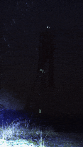 a dark night scene with a light shining on the ground