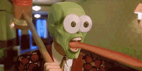 a man with a green mask on his face is sticking out his tongue .