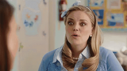 a woman in a blue sweater and headband is making a funny face while talking to another woman .