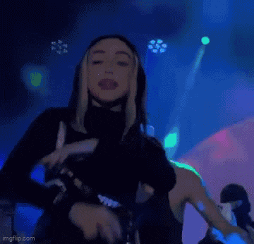 a woman is standing on a stage holding a microphone and dancing .