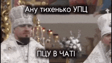 two priests are standing in a church and one of them is wearing a crown