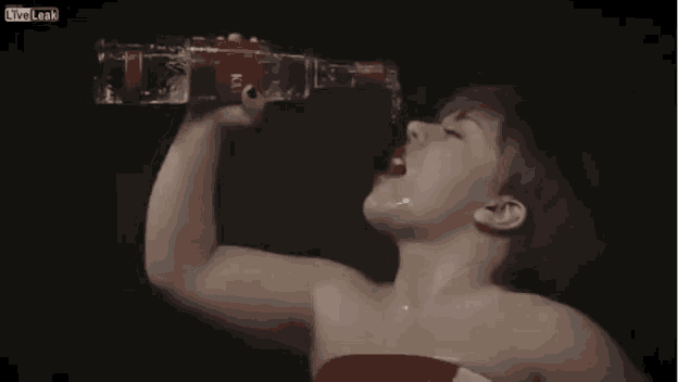 a woman is drinking water from a bottle with a red label .