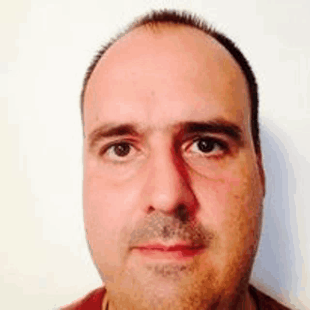 a close up of a man 's face with a beard against a white wall .