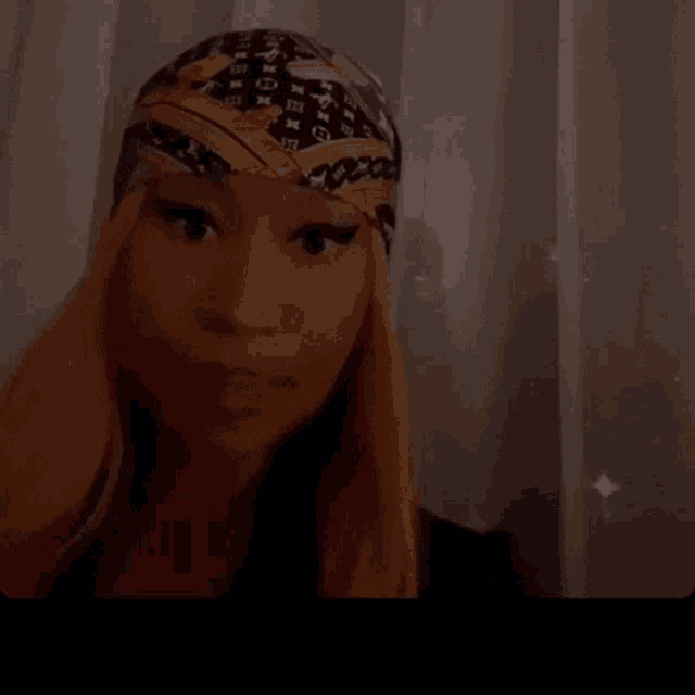 a woman wearing a louis vuitton head scarf looks at the camera